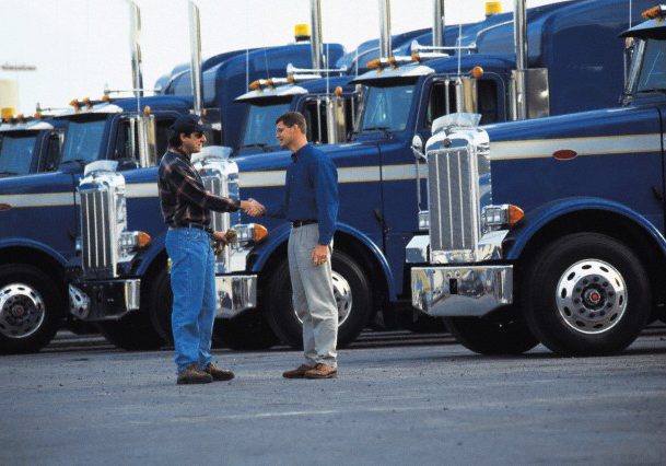 Truck drivers shaking hands in parking lot --- Image by © Ocean/Corbis